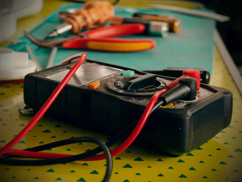 Multímetro con pinzas y herramientas de electricista sobre una mesa